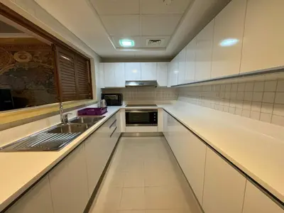 a white kitchen with white cabinets and a sink at Lovely 3BHK with private beach in Dubai