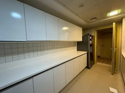 a kitchen with white cabinets and a black refrigerator at Lovely 3BHK with private beach in Dubai