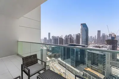 a chair on a balcony with a view of a city at Exclusive Burj Khalifa View - Modern 1 BR in Dubai