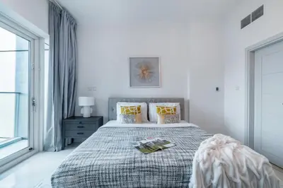 a white bedroom with a large bed with yellow pillows at The Smart Concierge - Damac Heights in Dubai