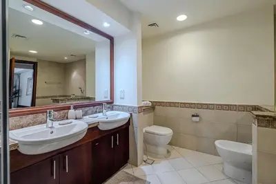 a bathroom with two sinks and a toilet and a mirror at Apartment with Palm Jumeirah view I Golden Mile in Dubai