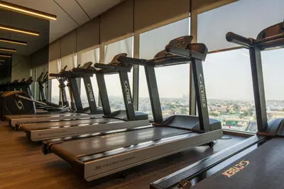 a row of treadmills in a gym with windows at Knokey Aykon City in Dubai