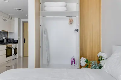 a bedroom with a white bed and a kitchen at Knokey Aykon City in Dubai