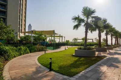 a walkway with palm trees and a building at Knokey Aykon City in Dubai