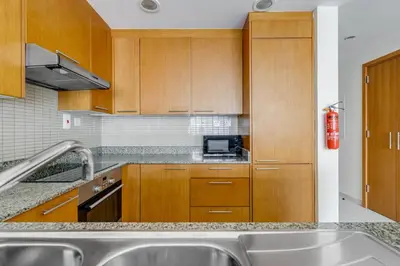 a kitchen with wooden cabinets and a sink at Knokey Bay Square in Dubai
