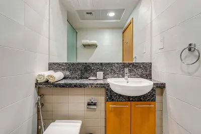 a white bathroom with a sink and a toilet at Knokey Bay Square in Dubai