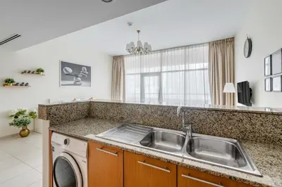 a kitchen with a sink and a washing machine at Knokey Bay Square in Dubai