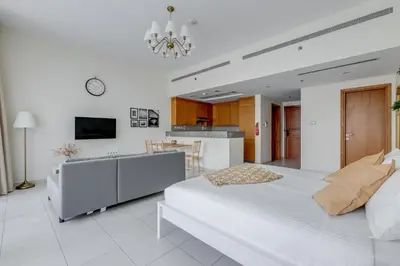 a white bedroom with a large bed and a kitchen at Knokey Bay Square in Dubai