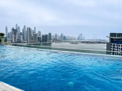 a swimming pool on top of a building with a city at Chic Living 1 BHK with Beach Access in Dubai