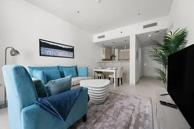 a living room with a blue couch and a table at Chic Living 1 BHK with Beach Access in Dubai