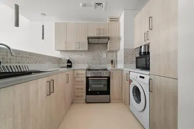 a kitchen with a stove and a washer and dryer at Chic Living 1 BHK with Beach Access in Dubai