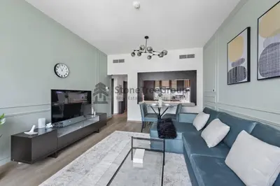 a living room with a blue couch and a table at Stylish 1 Br In Unique Location in Dubai
