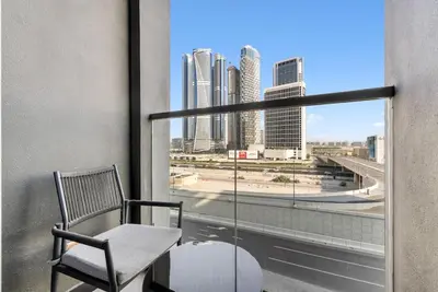 a chair on a balcony with a view of a city at Waves - Fully Equipped Studio for a Perfect Stay in Dubai in Dubai