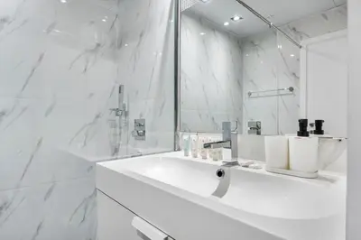 a white bathroom with a sink and a mirror at Sea View apt in JBR - 2 BR in front of the beach in Dubai