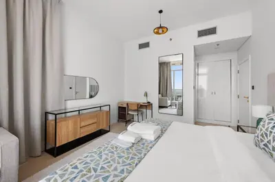 a bedroom with a large white bed and a desk at Unique 1 BHK Near To Metro in Dubai