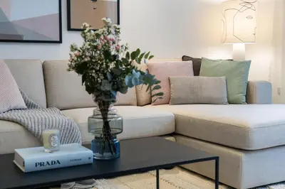 a living room with a couch with a vase of flowers on a table at 2BR API 1000 Community View Jumeirah in Dubai