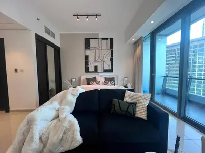 a living room with a blue couch with a blanket at The Smart Concierge - Silverene in Dubai