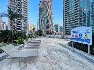 a row of lounge chairs and a sign in front of tall buildings at The Smart Concierge - Silverene in Dubai
