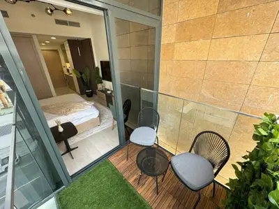 a room with a balcony with two chairs and a bed at Chic and Cozy Studio in Dubai
