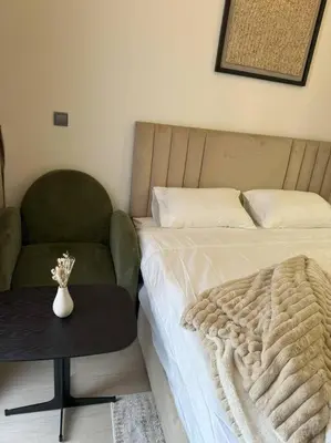 a bedroom with a bed and a chair and a table at Chic and Cozy Studio in Dubai