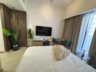 a bedroom with a large white bed and a television at Chic and Cozy Studio in Dubai