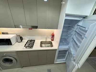 a kitchen with a sink and an open refrigerator at Chic and Cozy Studio in Dubai