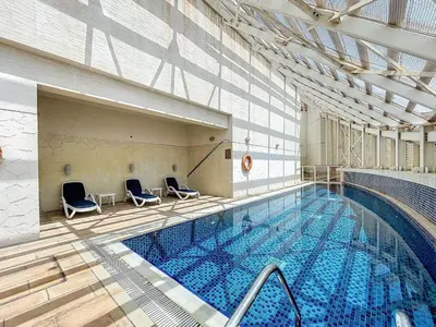 a large swimming pool with chairs in a building at The Bridge - Tranquil Two Bedroom in Sports City in Dubai