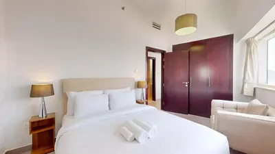 a bedroom with a white bed and a couch at The Bridge - Tranquil Two Bedroom in Sports City in Dubai