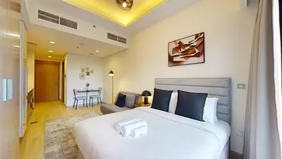 a bedroom with a large white bed and a living room at Azizi Riviera 9 - Bright Studio in Meydan in Dubai