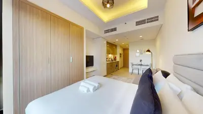 a bedroom with a white bed and a television at Azizi Riviera 9 - Bright Studio in Meydan in Dubai