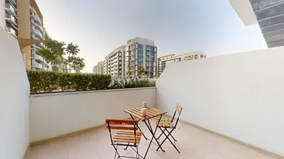 a table and chairs on a balcony with buildings at Azizi Riviera 9 - Bright Studio in Meydan in Dubai