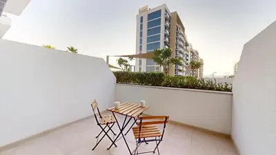 a table and chairs on a balcony with a building at Azizi Riviera 9 - Bright Studio in Meydan in Dubai