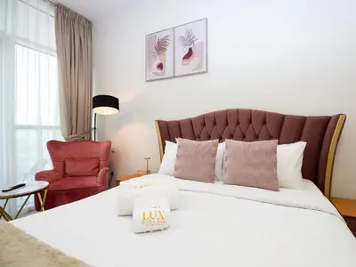 a bedroom with a large bed and a red chair at Cozy and Stylish Studio Retreat in DAMAC Hills in Dubai