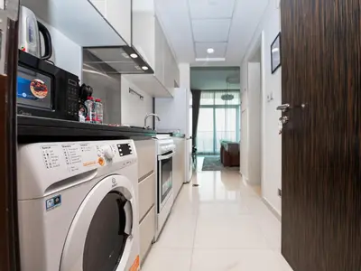a kitchen with a washer and dryer in a room at Cozy and Stylish Studio Retreat in DAMAC Hills in Dubai