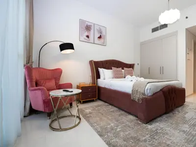 a bedroom with a bed and a chair at Cozy and Stylish Studio Retreat in DAMAC Hills in Dubai