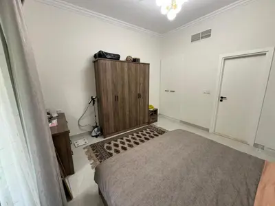 a bedroom with a bed and a wooden cabinet at Lovely Brand new 3 BR with maids room in Dubai