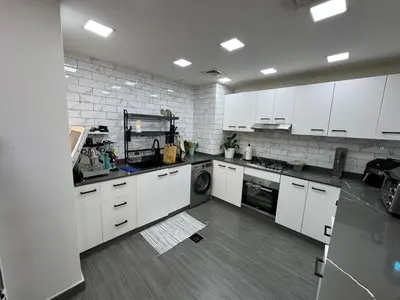 a large kitchen with white cabinets and a dishwasher at Lovely Brand new 3 BR with maids room in Dubai