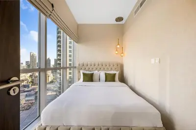 a bed in a room with a large window at Durrani Homes - Lumina Grand 3BR with Burj khalifa and Fountain Views in Dubai