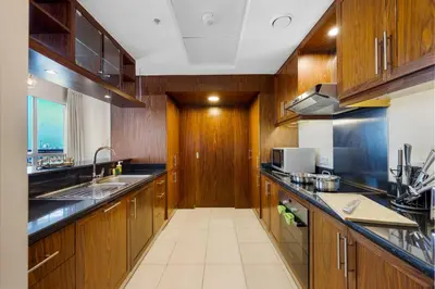 a large kitchen with wooden cabinets and a sink at Durrani Homes - Lumina Grand 3BR with Burj khalifa and Fountain Views in Dubai