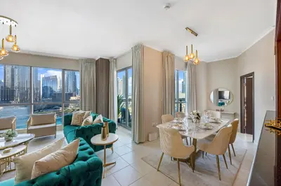 a living room with a green couch and a table and chairs at Durrani Homes - Lumina Grand 3BR with Burj khalifa and Fountain Views in Dubai