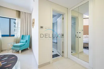 a hotel room with a blue chair and a mirror at Lovely 2BR at The Signature, Downtown Dubai by Deluxe Holiday Homes in Dubai