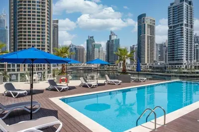 a pool with chairs and umbrellas and a city skyline at Dubai Marina, LIV Residence, Luxury Studio Apartment in Dubai