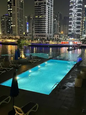 a swimming pool in the middle of a city at night at Dubai Marina, LIV Residence, Luxury Studio Apartment in Dubai