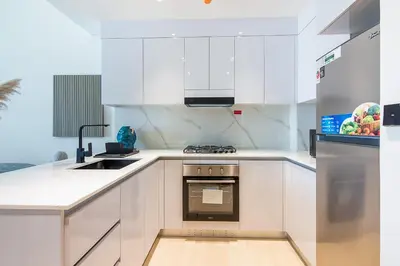 a kitchen with white cabinets and a stove top oven at Binghatti Emerald, JVC- Charming 1-BR Apartment in Dubai