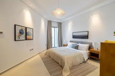 a white bedroom with a bed and a chandelier at 2BR API 1000 Community View Jumeirah in Dubai