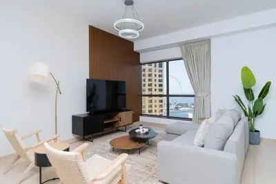 a living room with a white couch and a tv at Breathtaking Scenery- JBR Walk- Beach Access in Dubai
