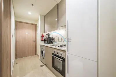 a kitchen with a stove and a refrigerator at Chic Studio in Azizi Riviera 44, Al Merkadh by Deluxe Holiday Homes in Dubai
