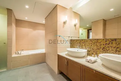 a bathroom with two sinks and a tub and a sink at Chic 2BR Apartment with Pool View in Marina Apartment 6, Palm Jumeirah by Deluxe Holiday Homes in Dubai