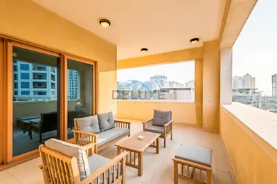 a balcony with chairs and tables and a large window at Chic 2BR Apartment with Pool View in Marina Apartment 6, Palm Jumeirah by Deluxe Holiday Homes in Dubai