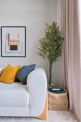 a living room with a white couch and a tree at New Cozy 1BR in the Heart of the City in Dubai